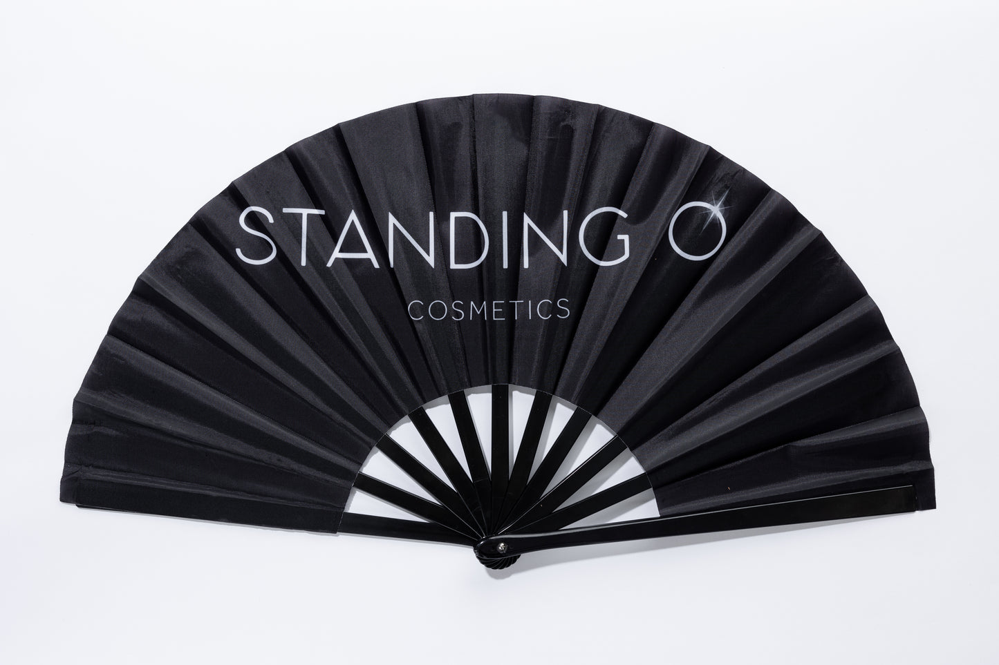 A close-up of a large hand fan in black with a white logo, reading Standing O Cosmetics.