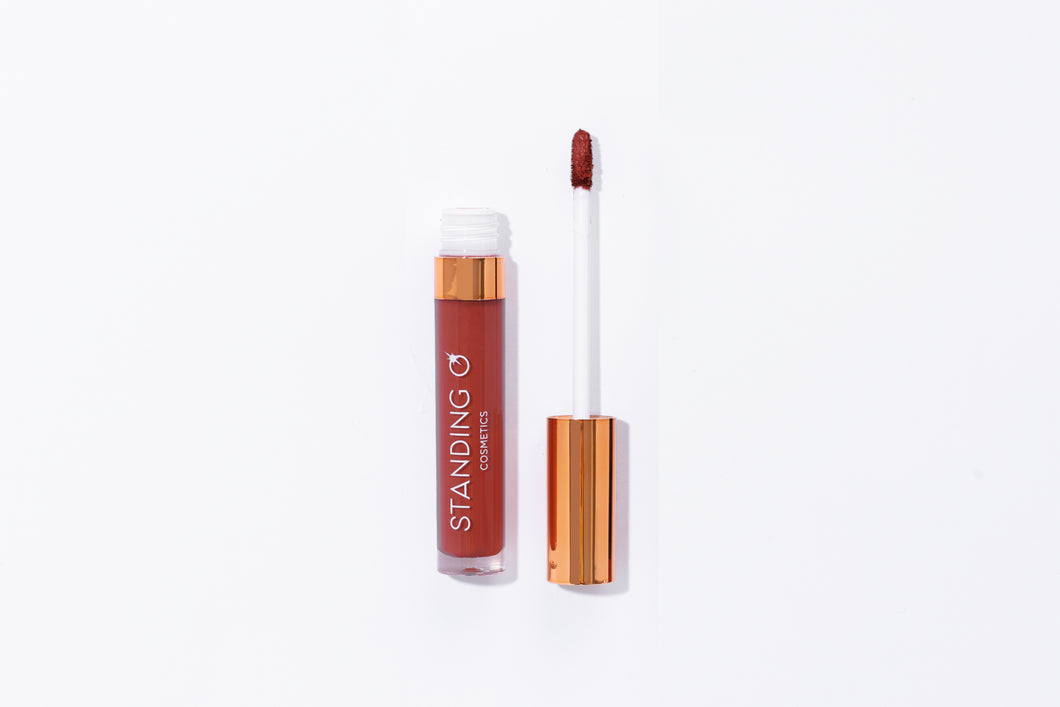 Tube of lipstick with a gold top shown open to showcase the applicator and color: classic burgundy lipstick.