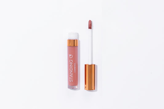 Tube of lipstick with a gold top shown open to showcase the applicator and color: rosey light nude lipstick.