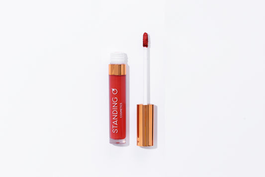 Tube of lipstick with a gold top shown open to showcase the applicator and color: classic red lipstick.