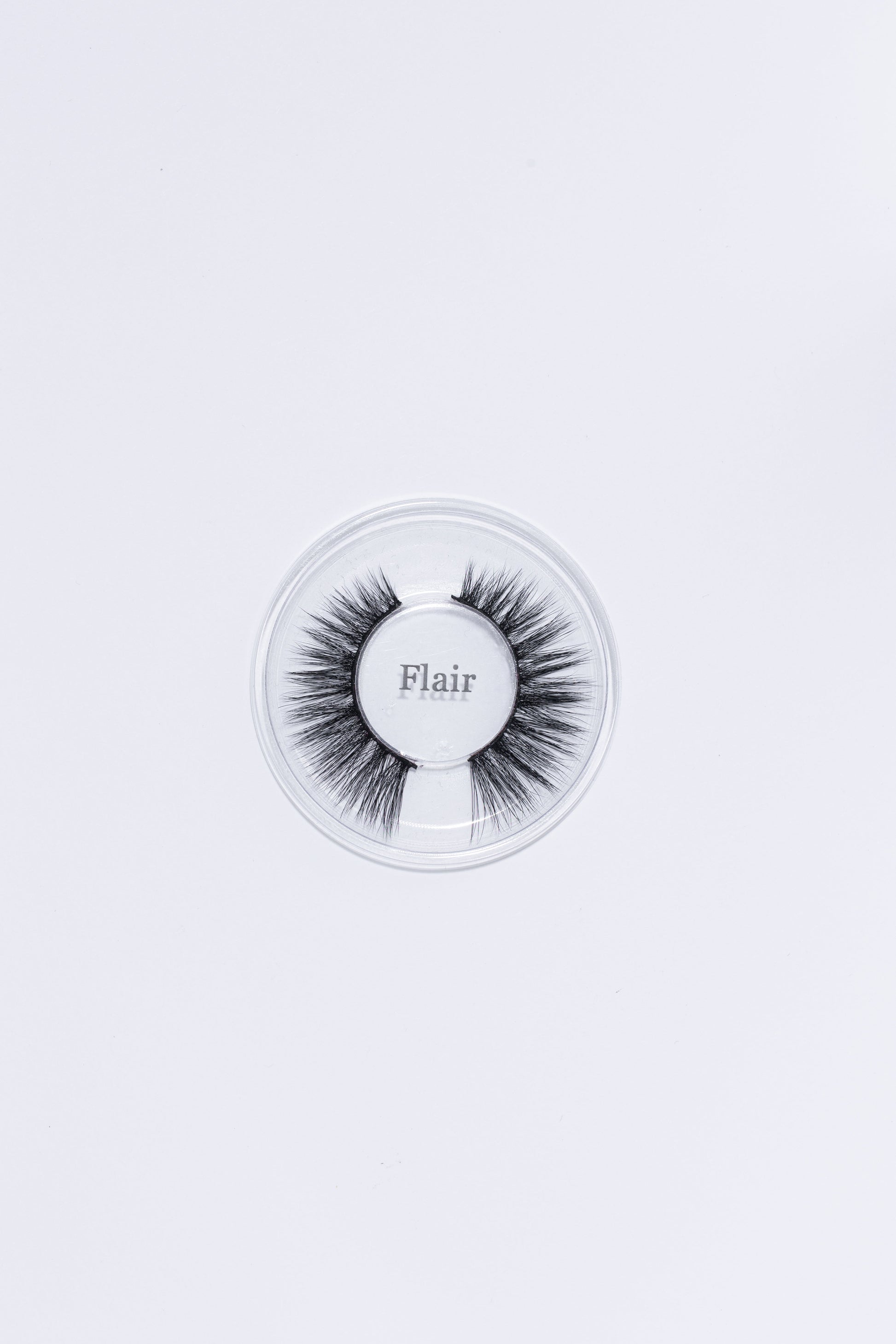 Clear plastic with Flair eyelashes on a white background, showcasing the shape of the lashes.